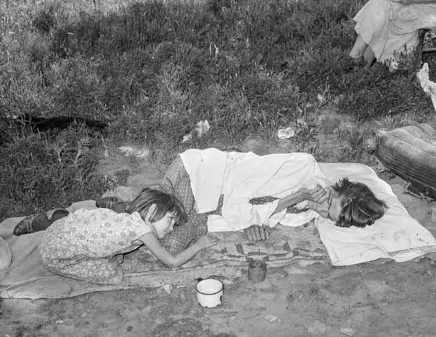 In 1939, amidst the lingering shadows of the Great Depression, a photograph taken near Spiro, Oklahoma, captured a haunting glimpse into the life of a tubercular mother and her frail daughter. The